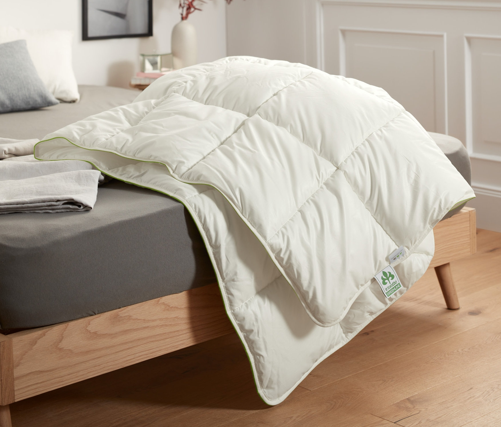 Une couette irisette® greenline garnie de fibres est posée sur un lit.
