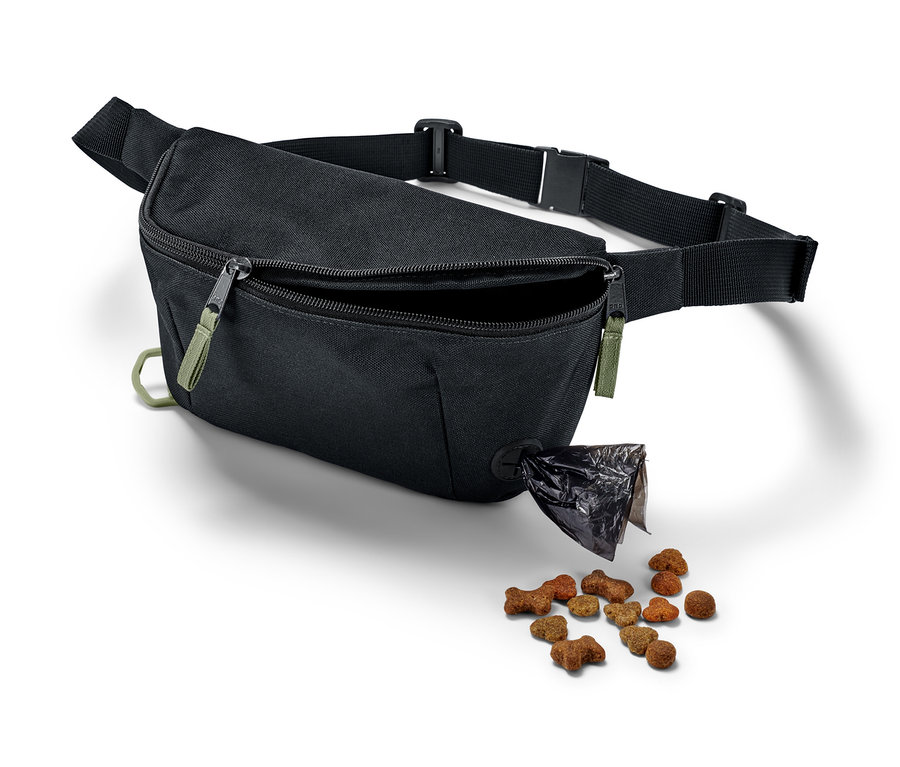 Un sac de promenade pour chien noir avec un compartiment ouvert d'où tombent des croquettes pour chien.
