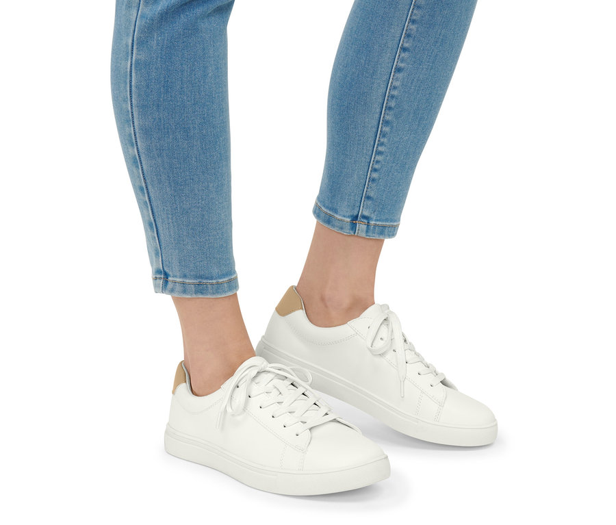 Jambes en jean bleu et baskets en cuir.