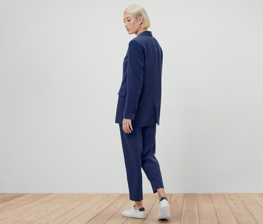 Femme posant en blazer en toile et pantalon.