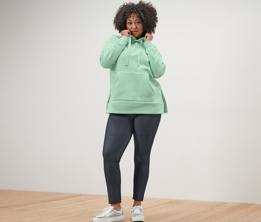 Femme portant un sweatshirt long à capuche et des leggings aspect jeans.