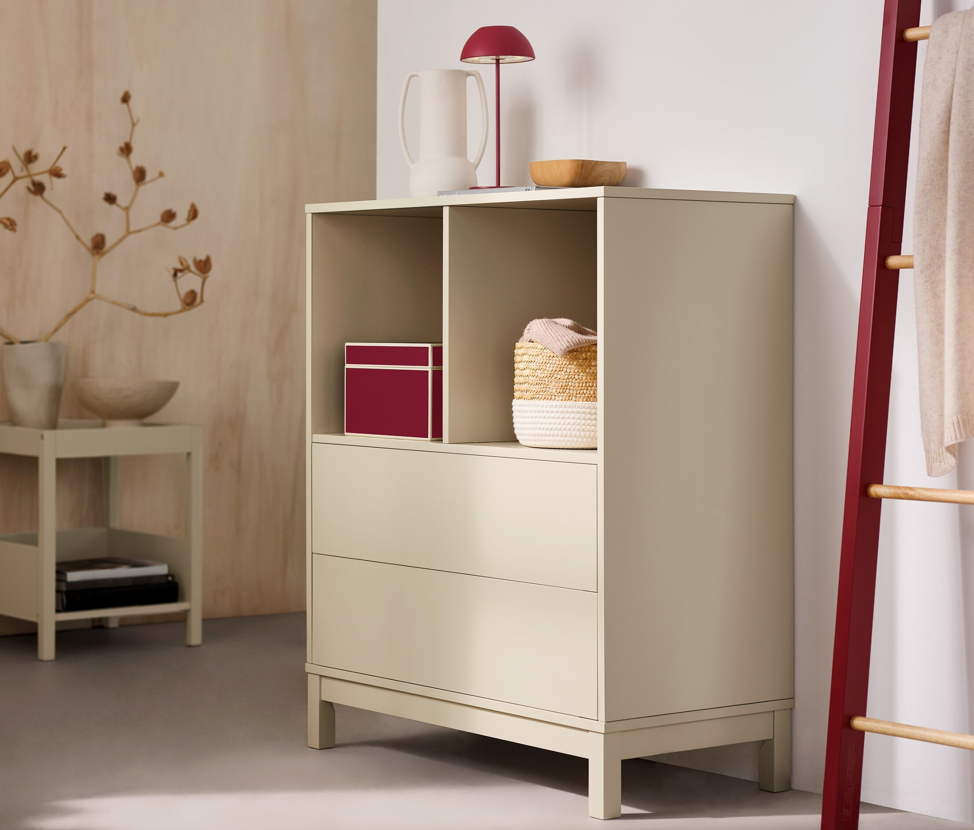 Dans la pièce, une commode haute avec 2 tiroirs et une lampe de table à LED sans fil rouge.