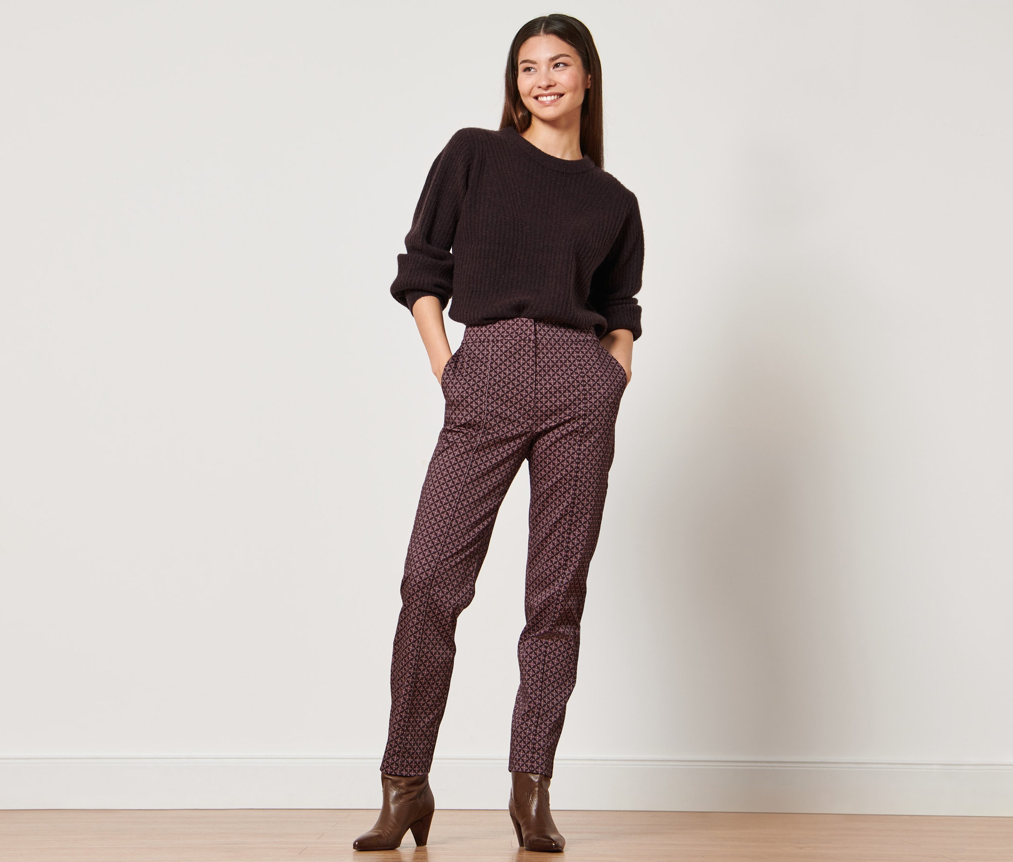 Femme posant en pull marron et pantalon tissé.