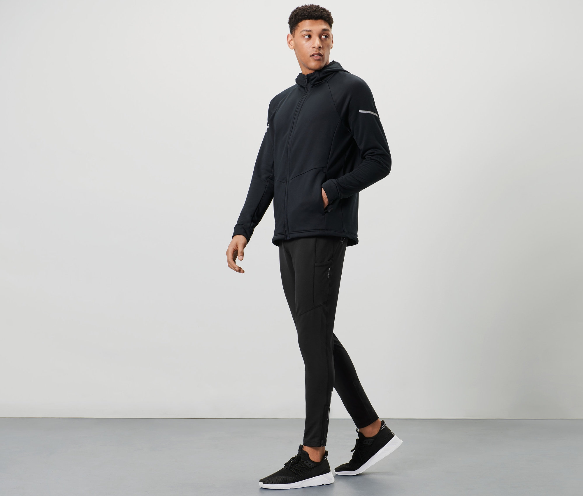 Un homme marche et porte un legging thermique noir et une veste.