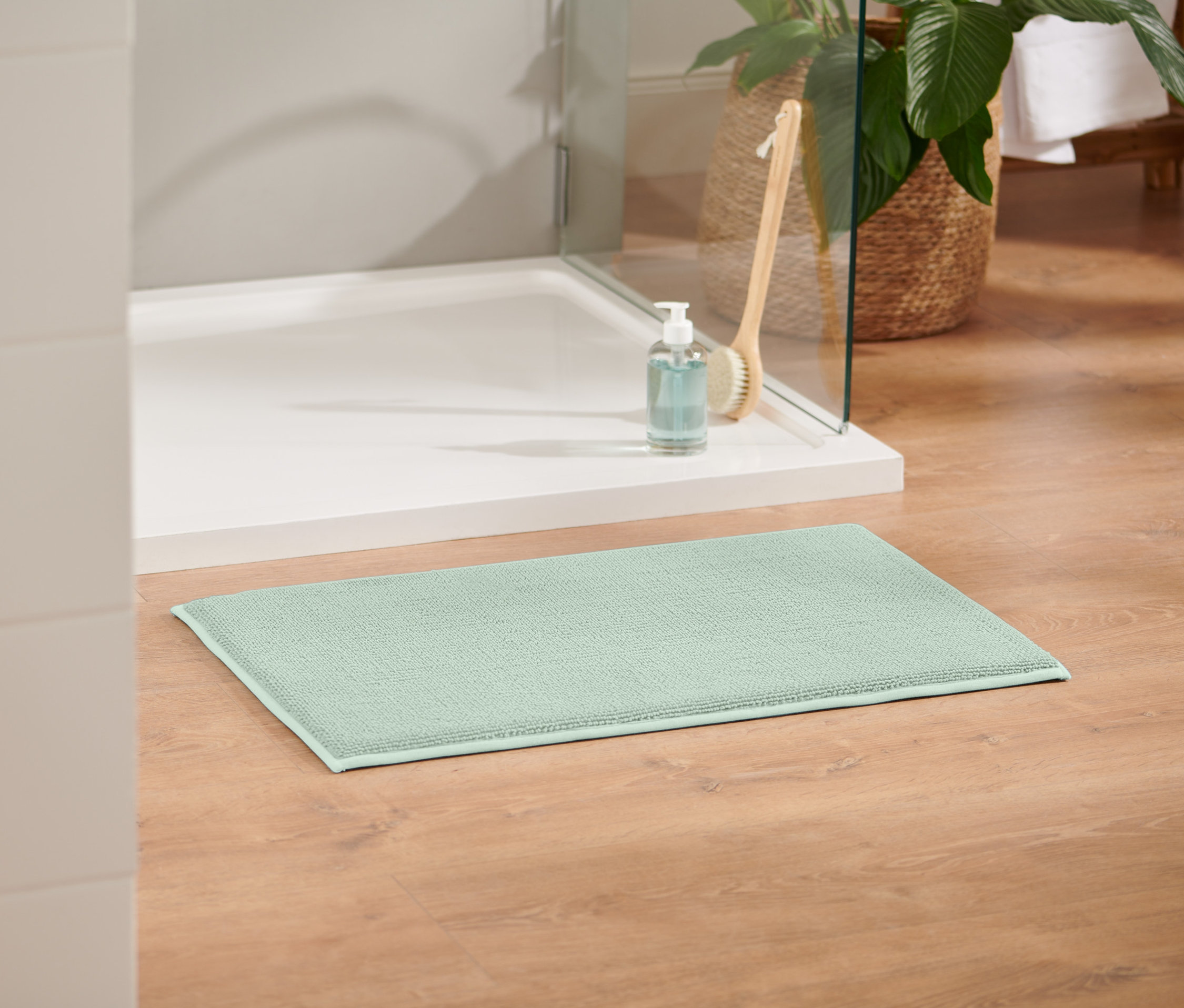 Un tapis de bain confortable vert de 40 x 70 cm est posé sur un plancher en bois.