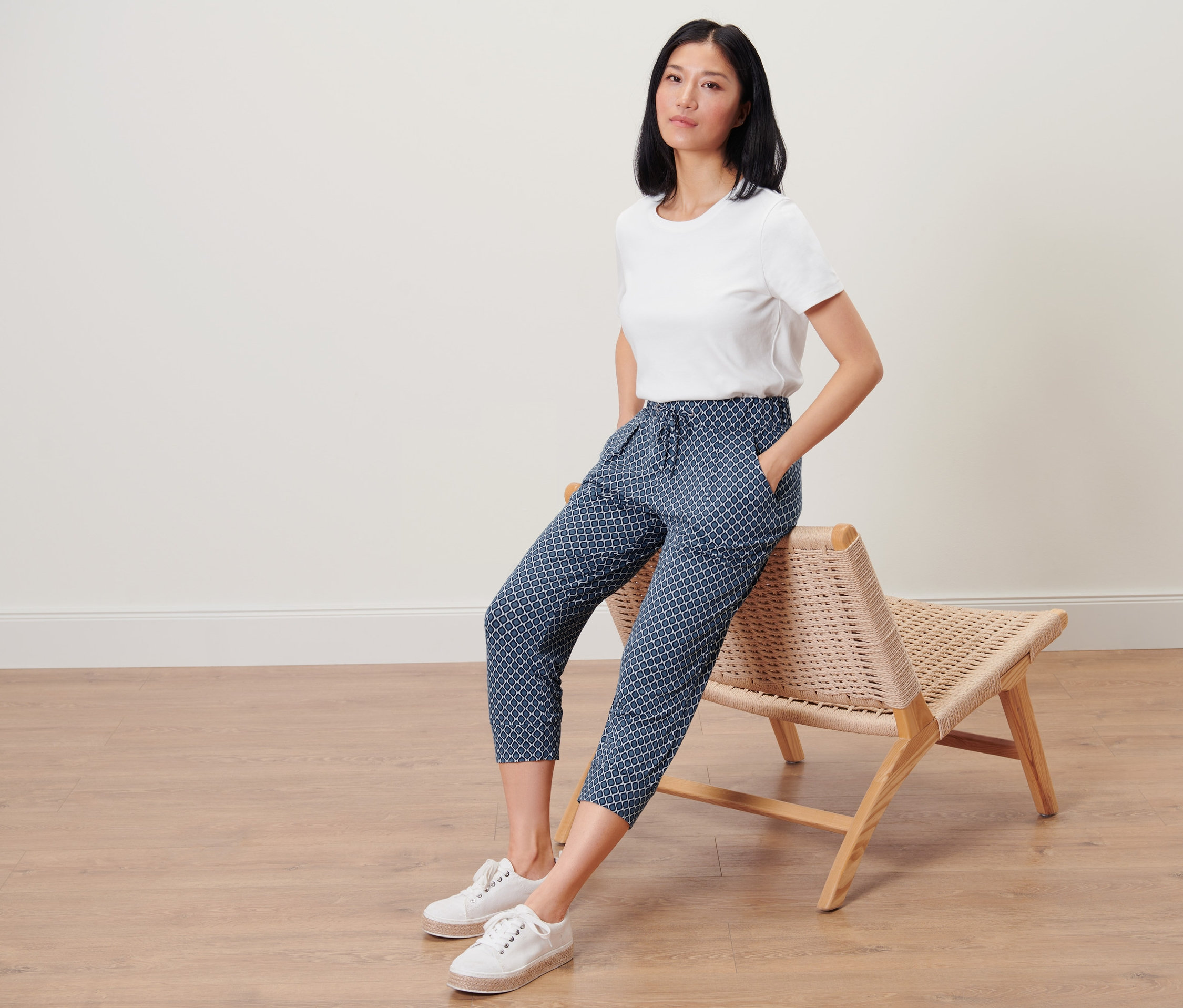 Femme assise sur une chaise portant un pantalon 3/4 en jersey imprimé.