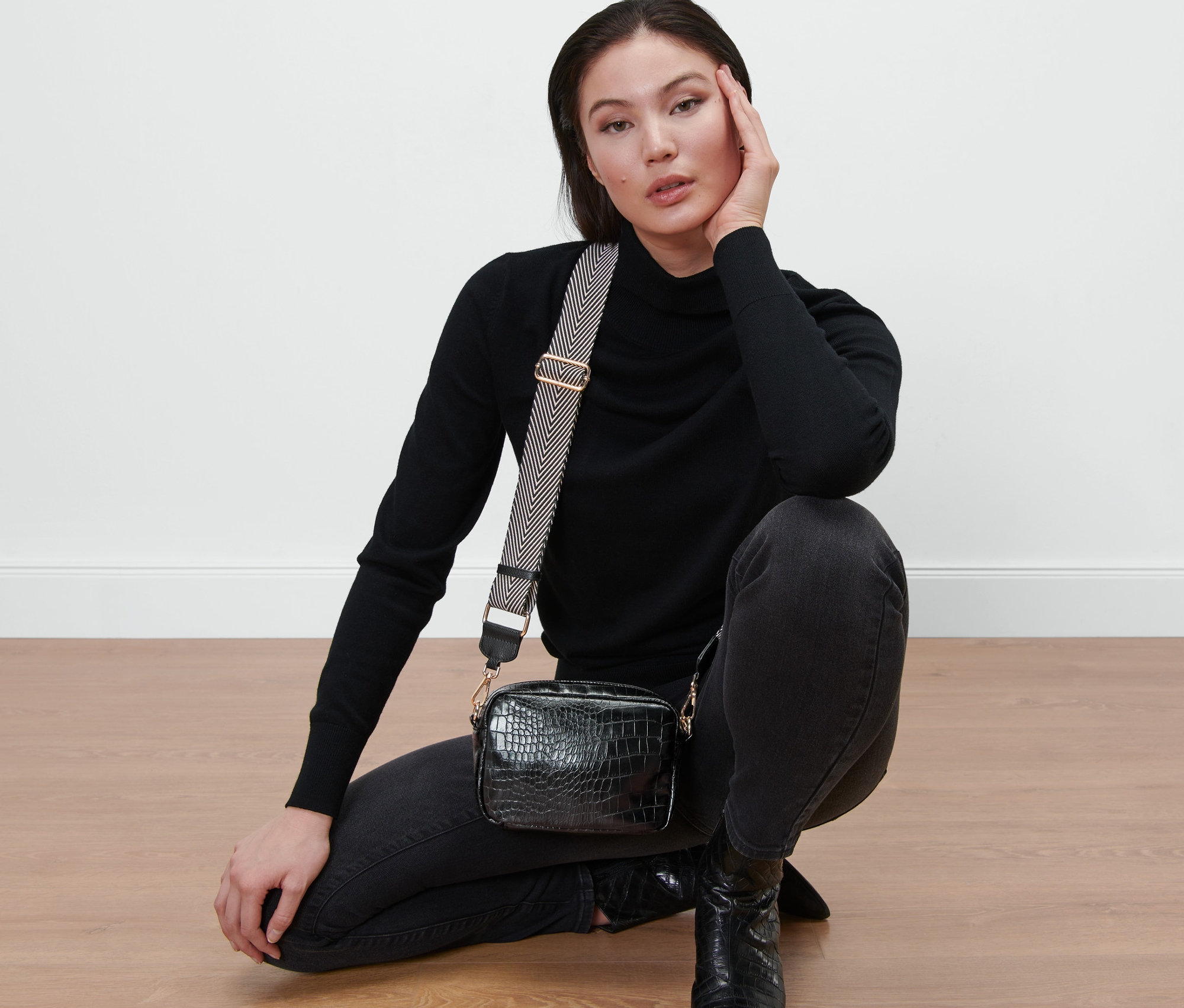Femme posant avec un sac noir et une bandoulière de rechange.