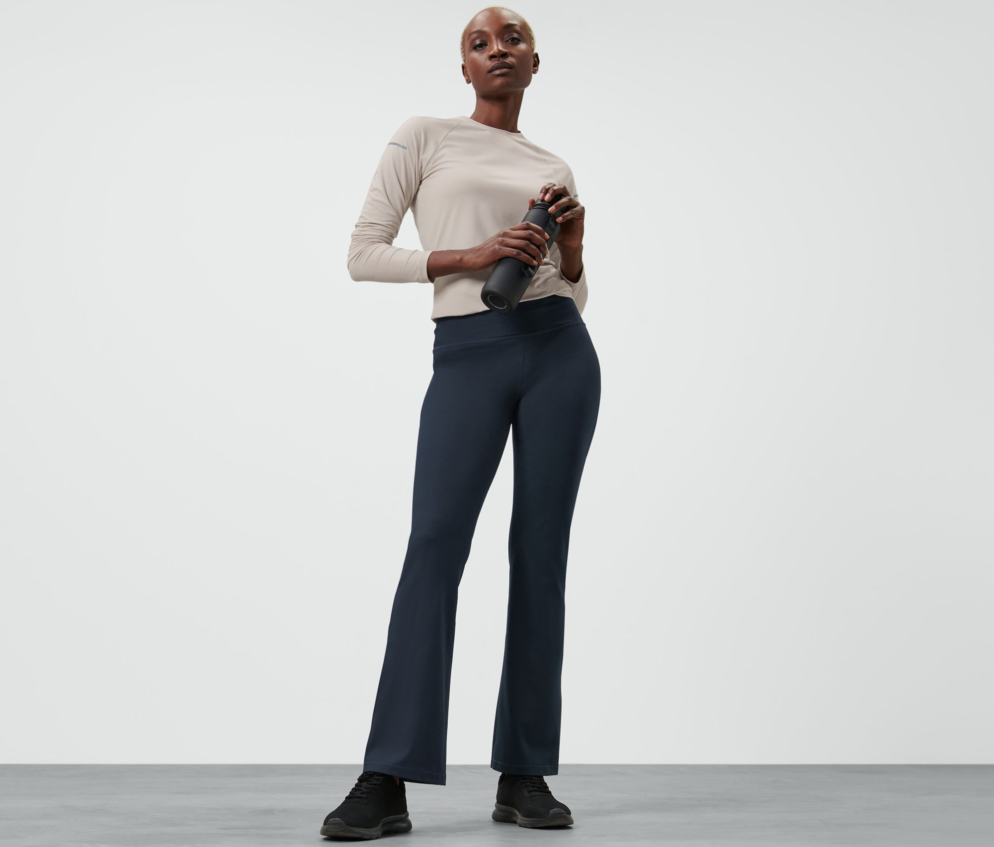 Femme tenant une bouteille d'eau et portant un pantalon de sport modelant.