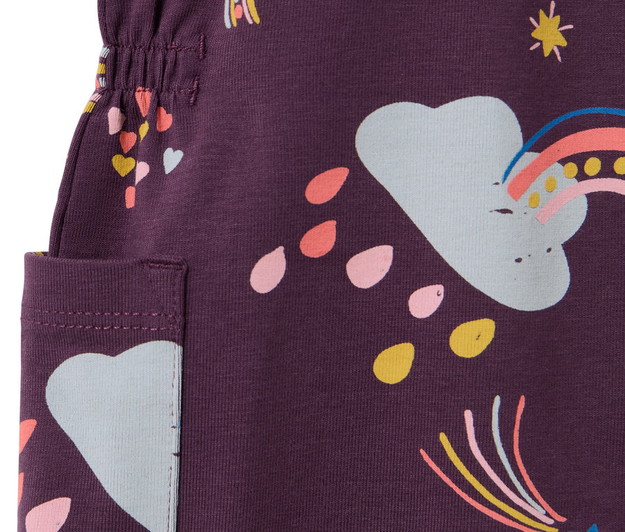 Gros plan sur une robe en jersey violette pour enfant, imprimée de motifs d'arcs-en-ciel, d'étoiles et de cœurs.