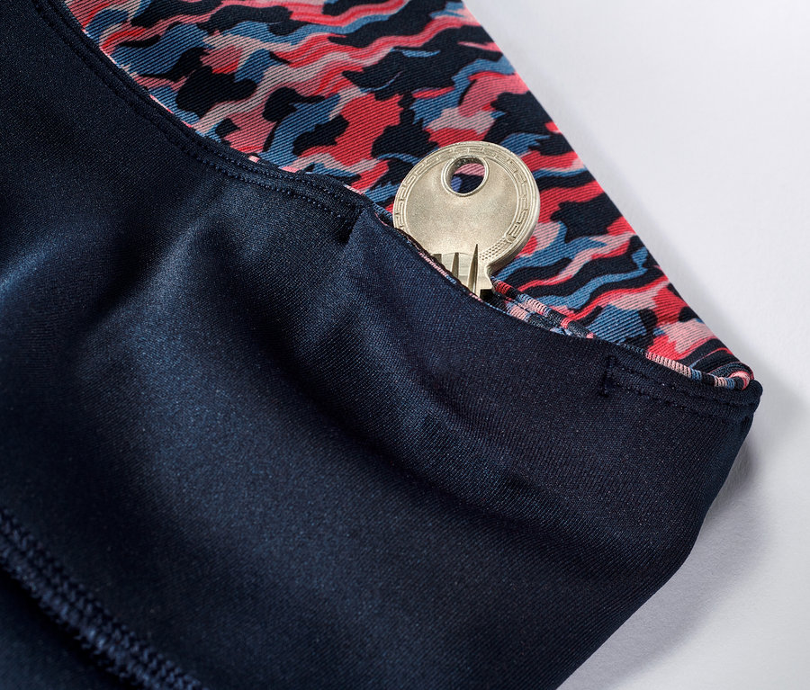 Détail d'un legging de sport réversible rose et bleu marine avec une clé dans la poche.