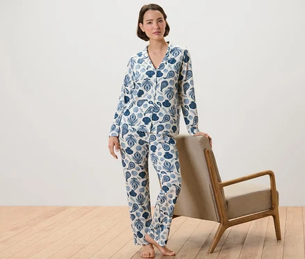 Femme en pyjama à imprimé coquillages et cachemire appuyée sur un fauteuil.