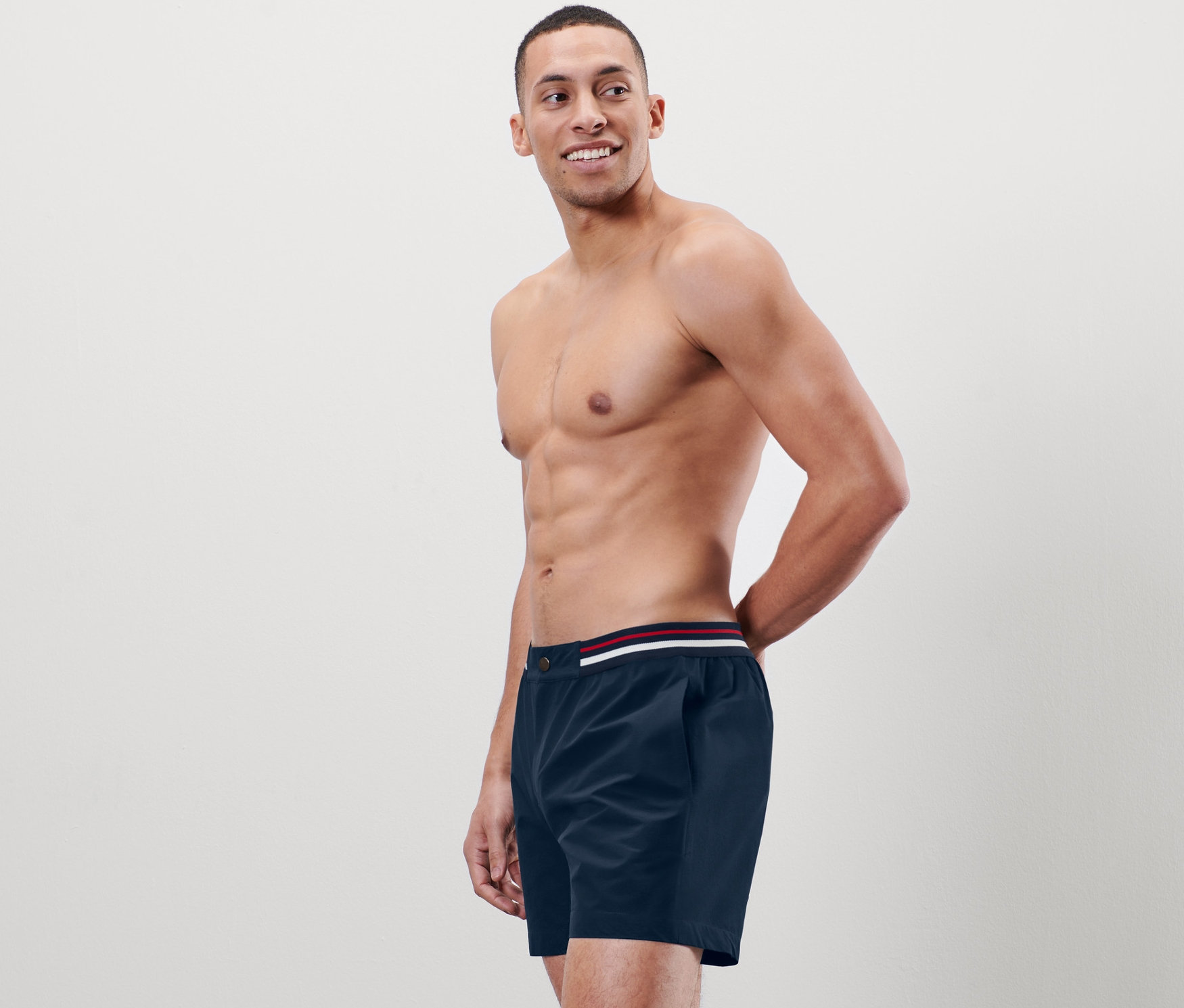Homme torse nu posant en short de bain.