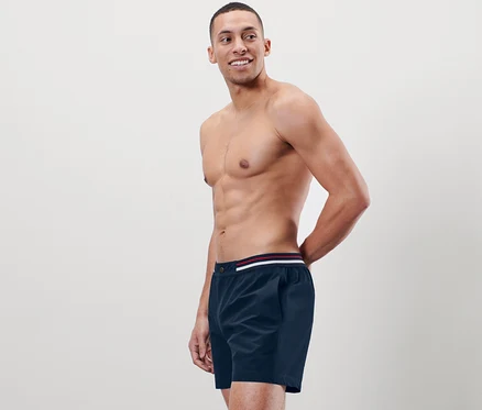 Homme torse nu posant en short de bain.
