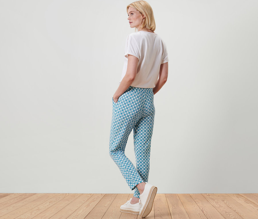 Une femme blonde, vue de dos, porte un pantalon en jersey avec motif intégral.