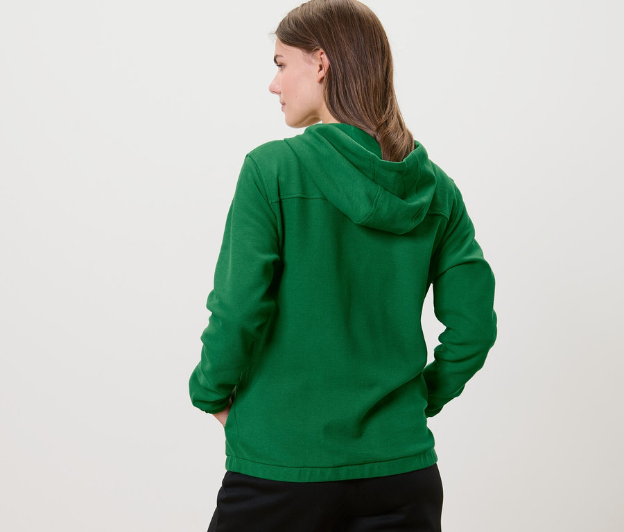 Une femme, vue de dos, porte une jaquette de survêtement verte.