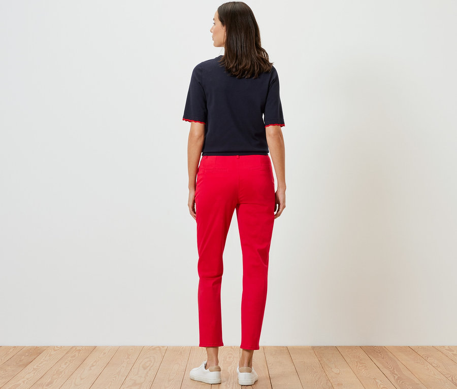 Femme posant de dos en pantalon chino rouge.