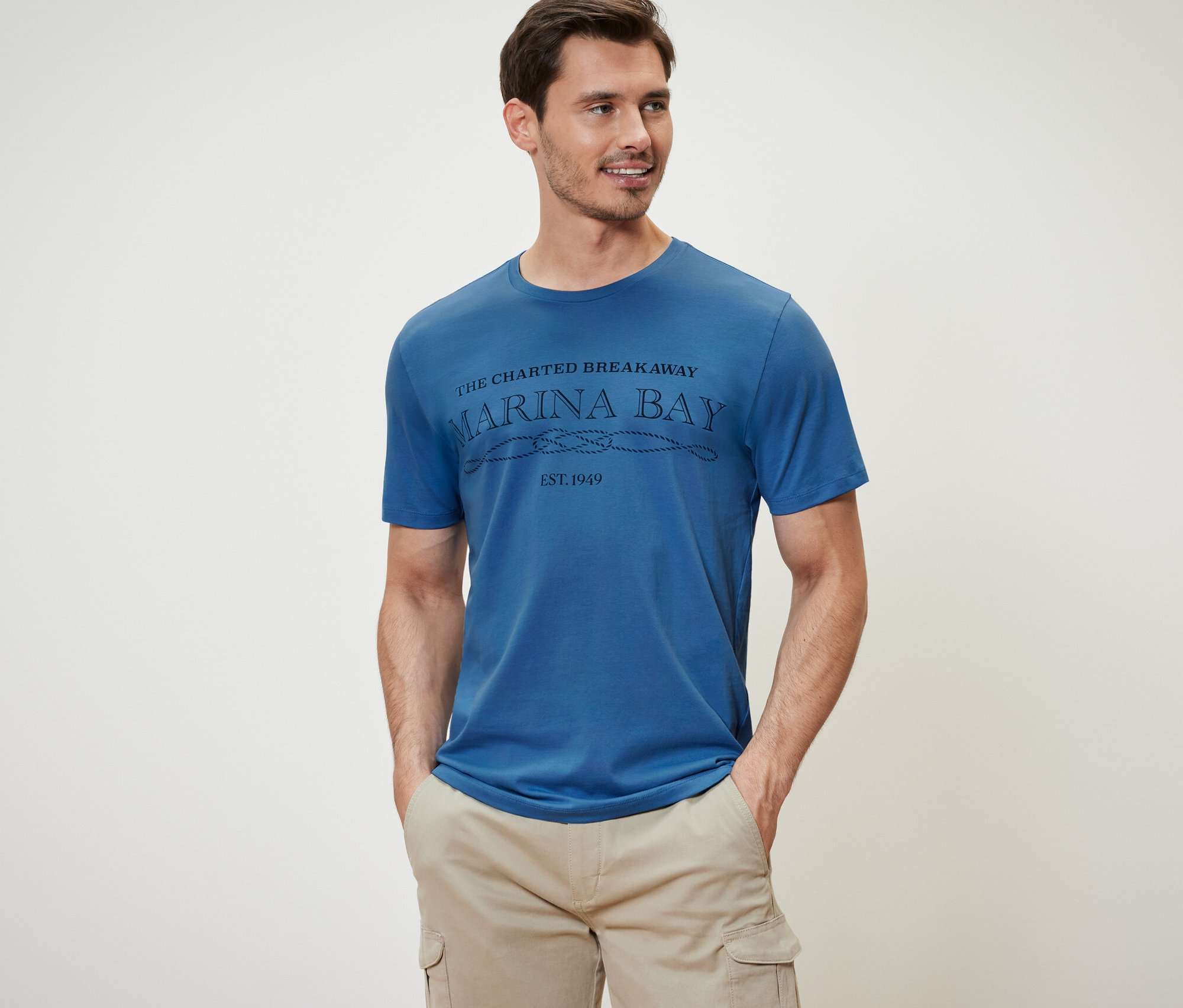 Un homme porte un t-shirt bleu et un short cargo beige.