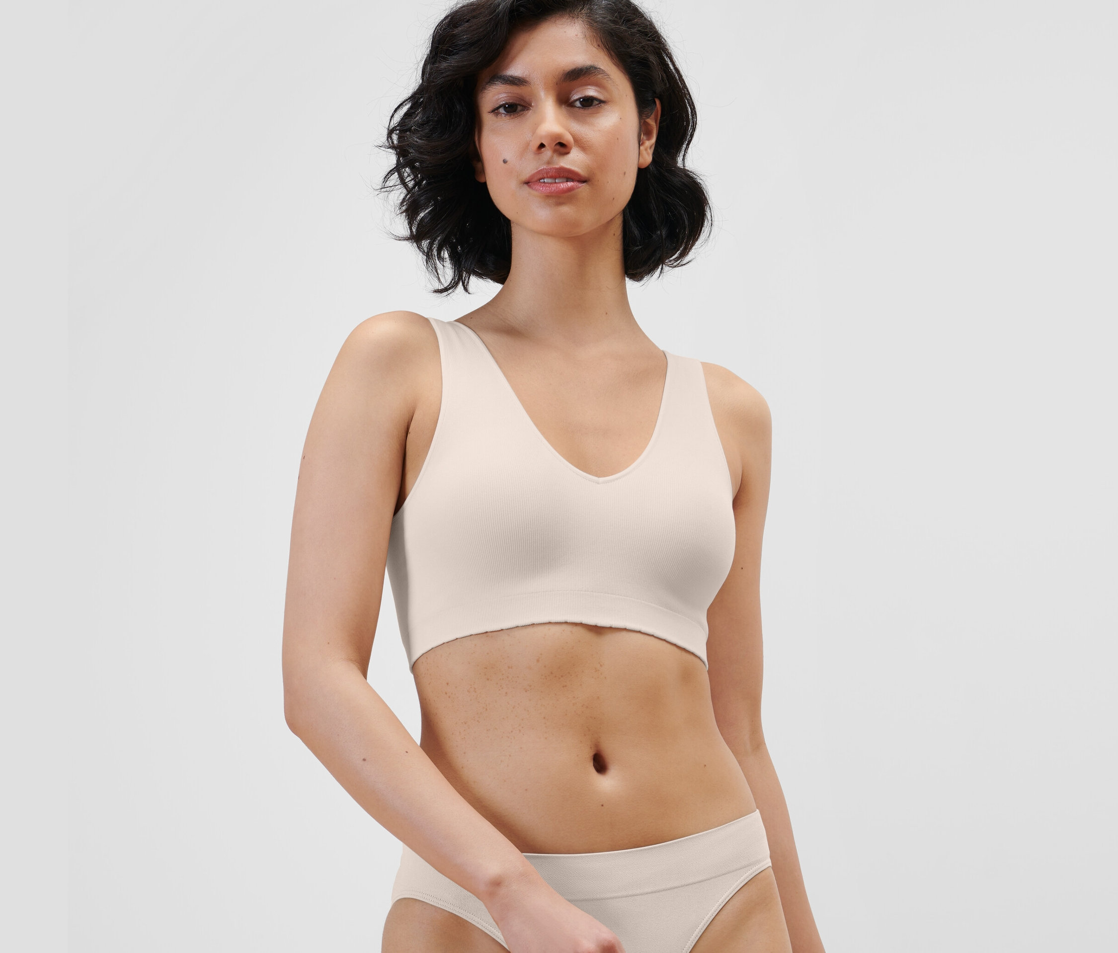 Une femme portant une brassière seamless crème et un bas assorti.