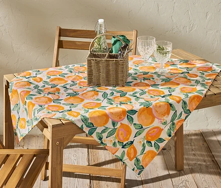 Sur une table en bois, une nappe lavable d'environ 90 x 90 cm, orange.