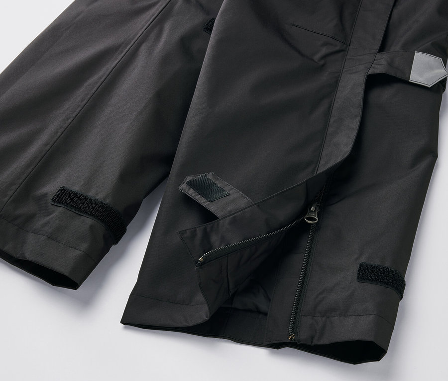Gros plan sur un pantalon de pluie high-tech noir avec fermeture éclair et velcro.