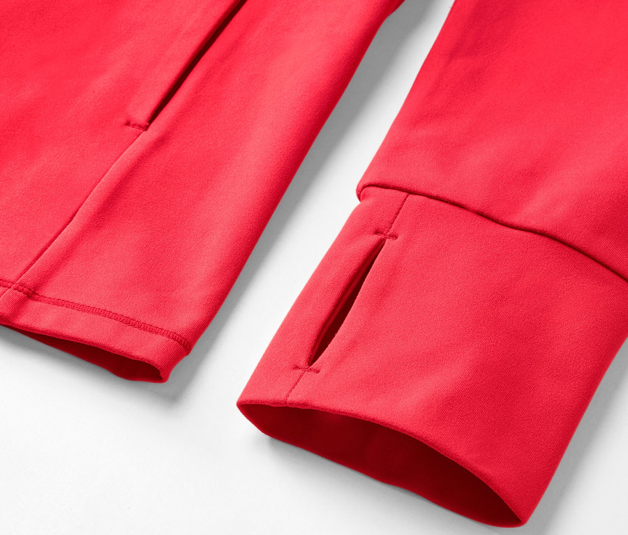 Gros plan sur une veste de survêtement rouge avec un trou pour le pouce et une poche.