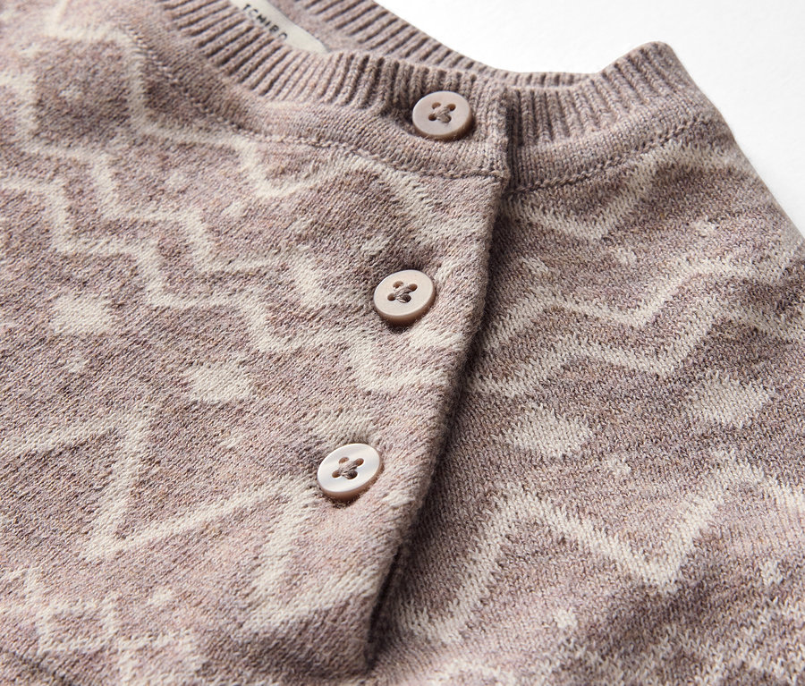 Gros plan sur un cardigan à motif géométrique avec des boutons.