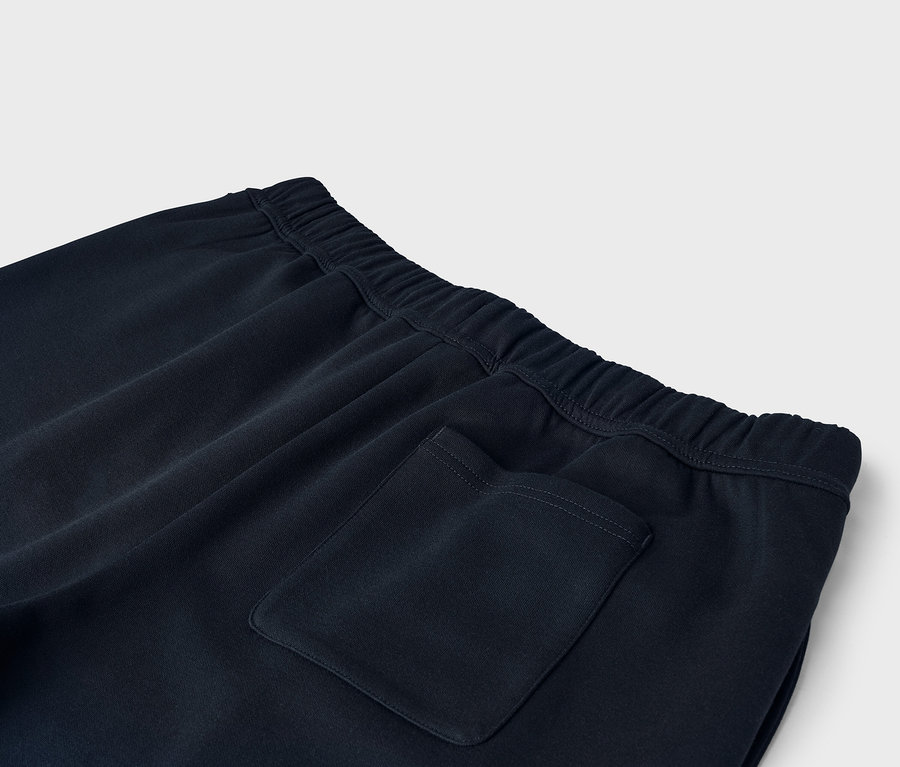 Gros plan sur un pantalon de survêtement bleu foncé avec une taille élastique et une poche arrière.