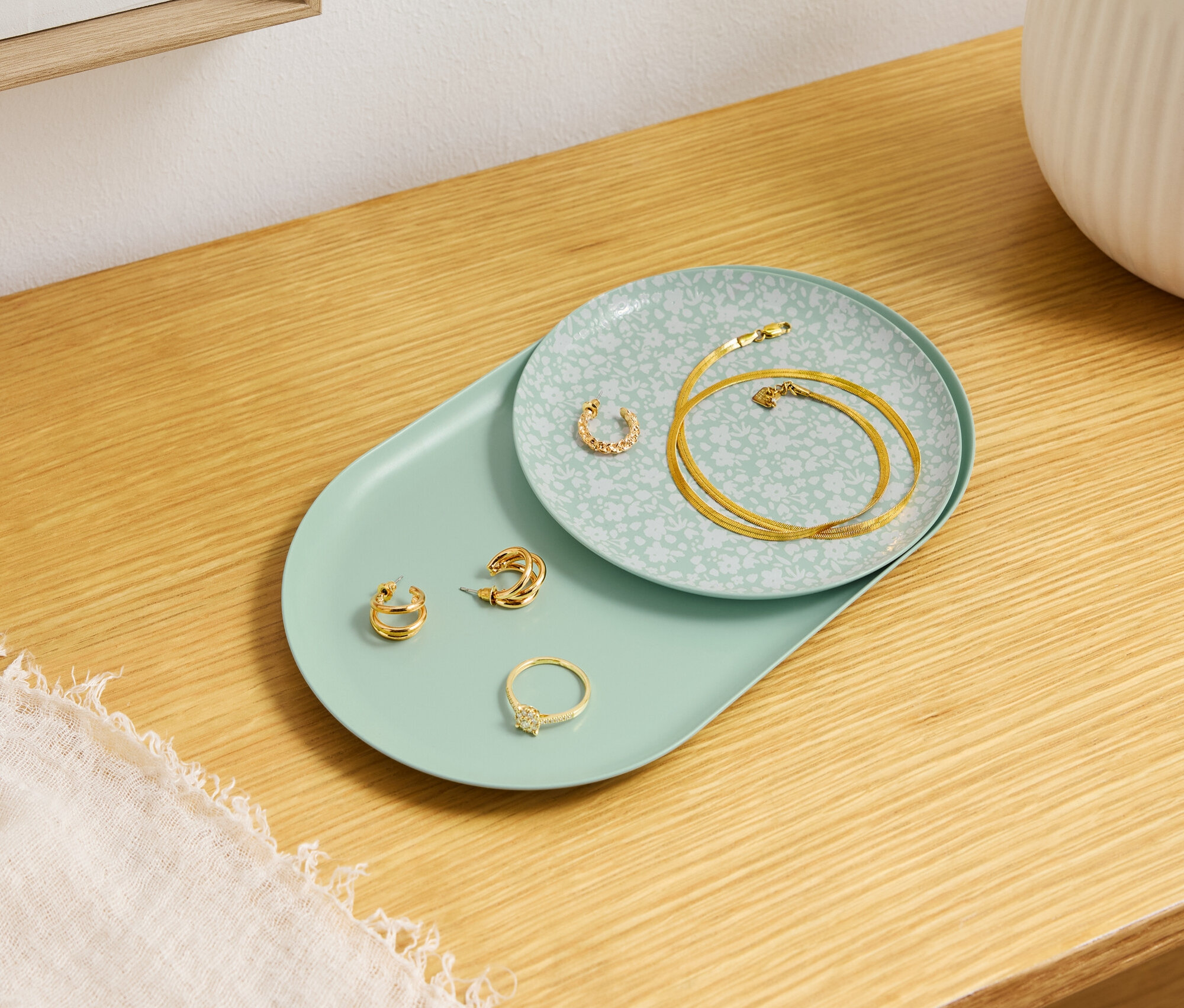 Des bijoux en or reposent sur des assiettes décoratives sur une table en bois.