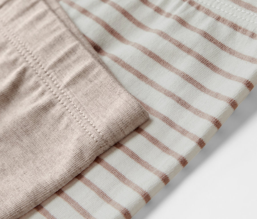 Gros plan sur 5 leggings enfant, un beige, l'autre à rayures marron.