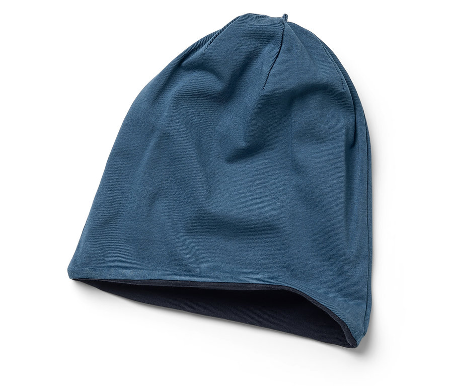 Un bonnet tricoté bleu est posé sur un fond blanc.