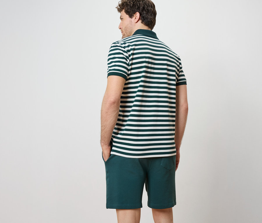 Un homme vu de dos porte un polo en tissu piqué rayé à manches courtes et un short.