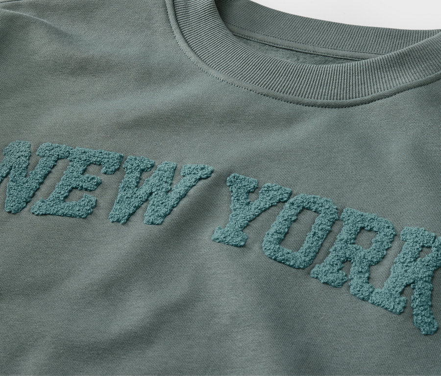 Gros plan sur un sweatshirt pour enfant avec un lettrage en tissu éponge NEW YORK.