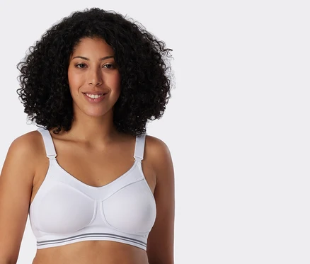 Une femme aux cheveux bouclés porte un soutien-gorge de sport blanc.
