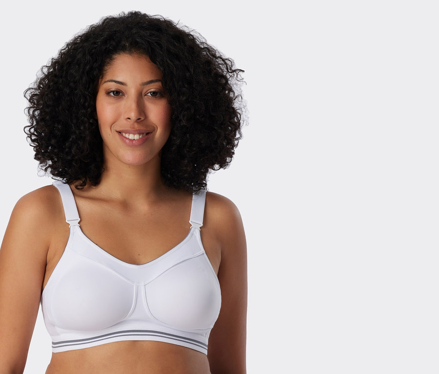 Une femme aux cheveux bouclés porte un soutien-gorge de sport blanc.