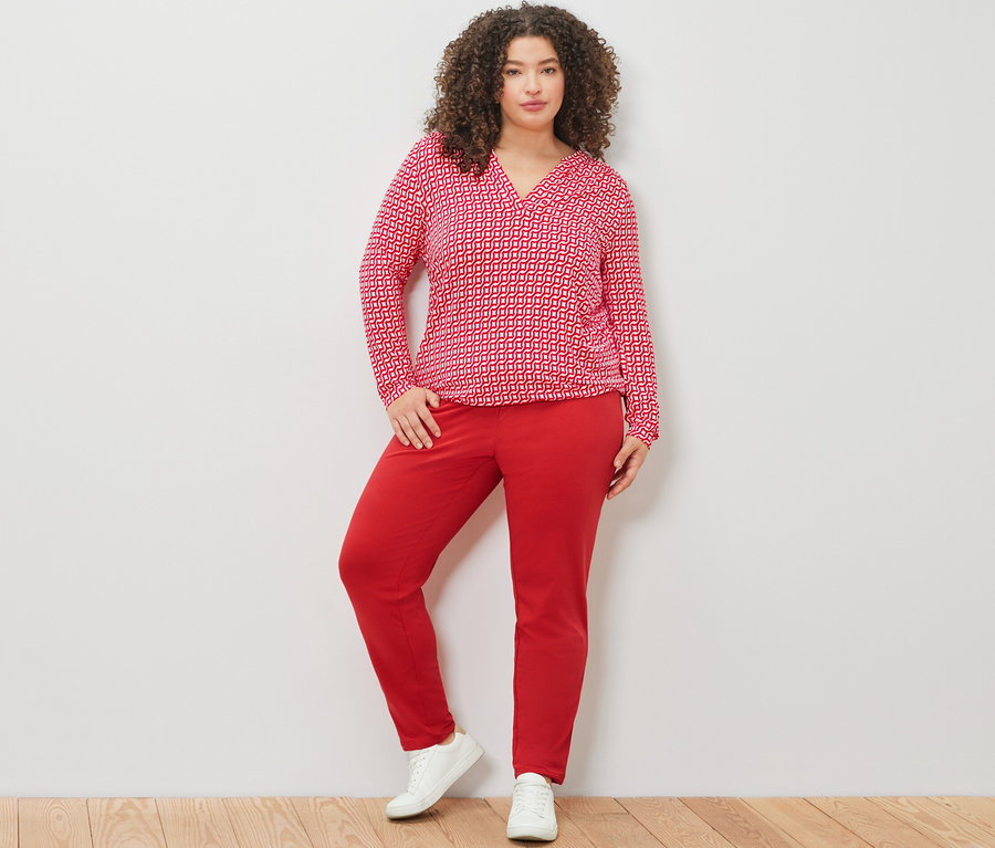 Femme posant en blouse imprimée rouge et pantalon de jogging rouge.