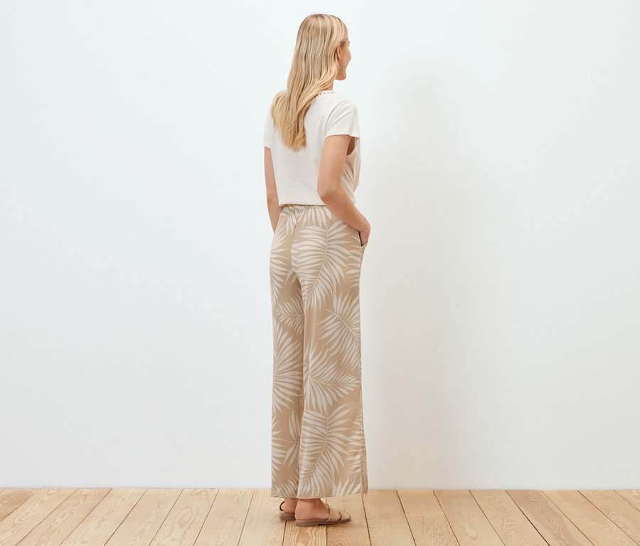 Une femme, vue de dos, porte un pantalon palazzo structuré avec imprimé intégral.