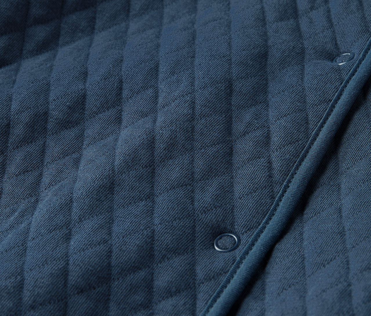 Gros plan sur une combinaison en jersey matelassé bleu pour bébé.