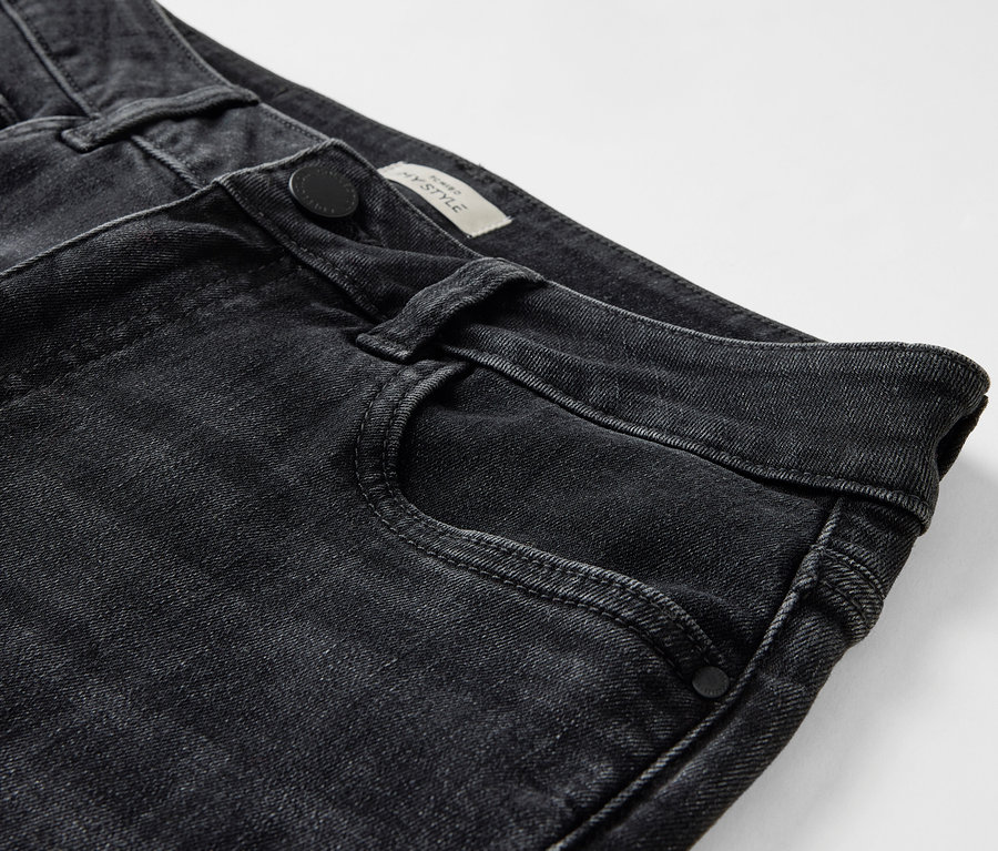 Détail de jeans noirs avec une fermeture à bouton et une poche avant.