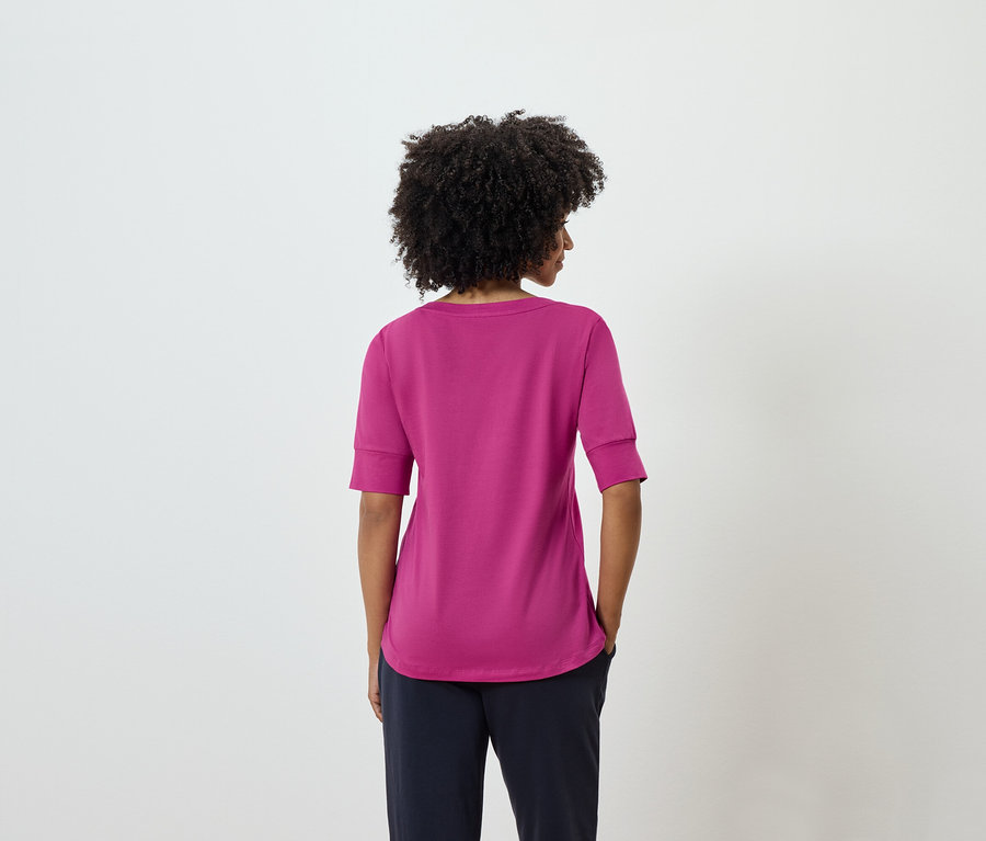 Vue arrière d'une femme avec une coiffure afro portant un t-shirt rose et un pantalon bleu marine.