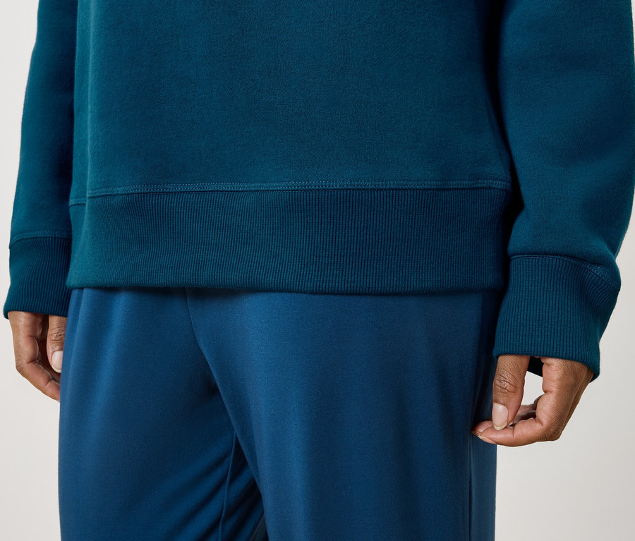 Une personne porte un sweat-shirt bleu-vert et un pantalon de survêtement bleu.