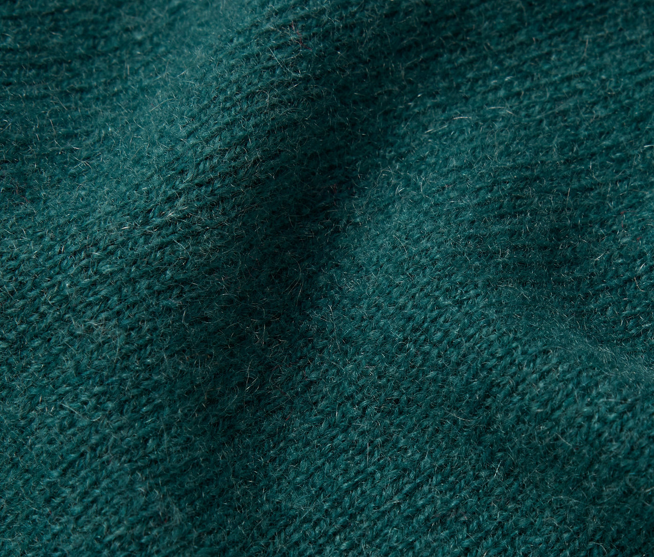 Gros plan sur la texture d'un tricot vert foncé.