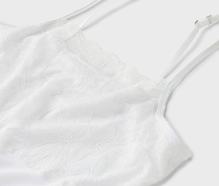 Gros plan sur un débardeur blanc en dentelle à bretelles spaghetti.