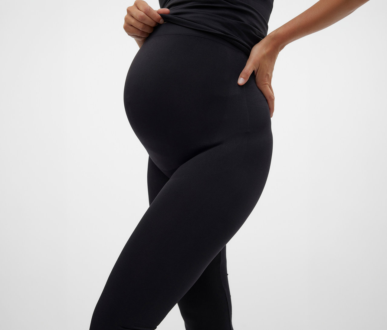 Femme enceinte portant un haut noir et un Skinny Leggings MAMALICIOUS «
MLTIA JEANNE » posant sur fond blanc.
