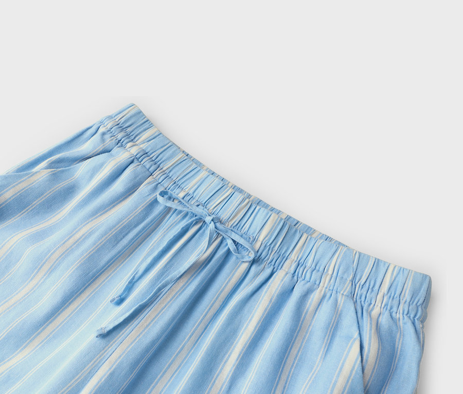 Gros plan de la taille d'un pantalon rayé bleu clair et blanc avec cordon de serrage.