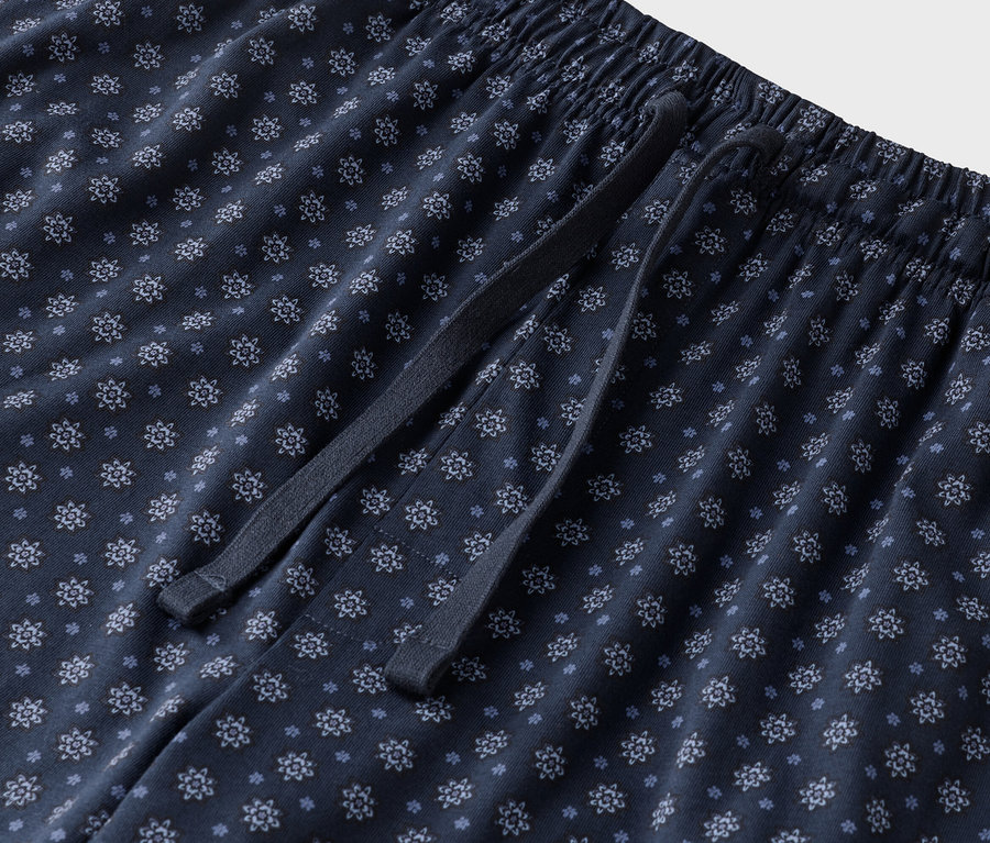 Gros plan d'un pantalon de pyjama bleu marine à motifs floraux avec cordon de serrage.