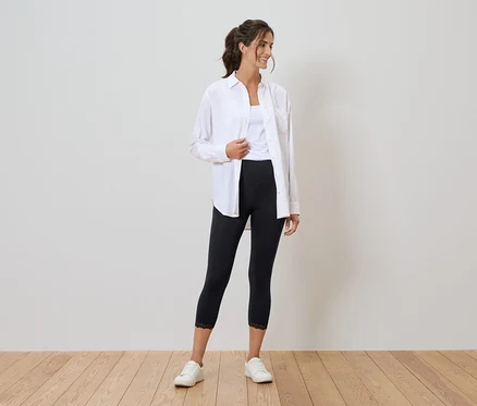 Femme portant une chemise blanche, un débardeur, un legging noir avec de la dentelle et des baskets blanches.