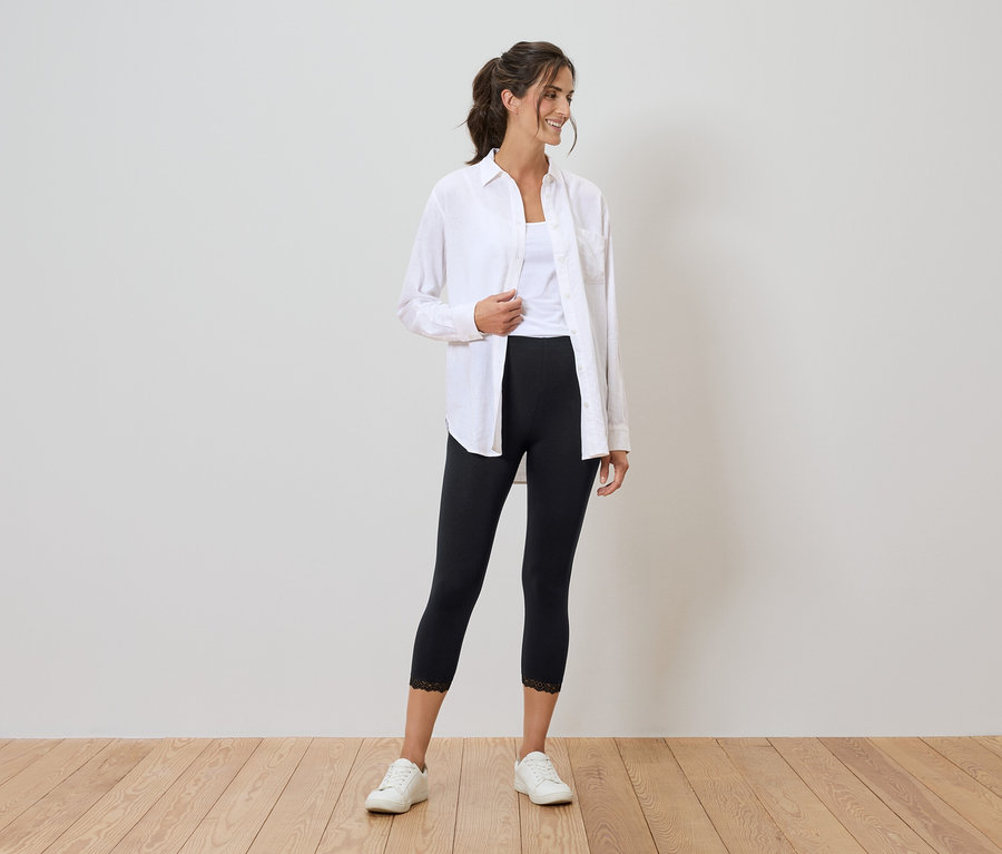 Femme portant une chemise blanche, un débardeur, un legging noir avec de la dentelle et des baskets blanches.