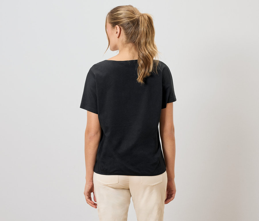 Femme vue de dos, portant un t-shirt noir et un pantalon clair.
