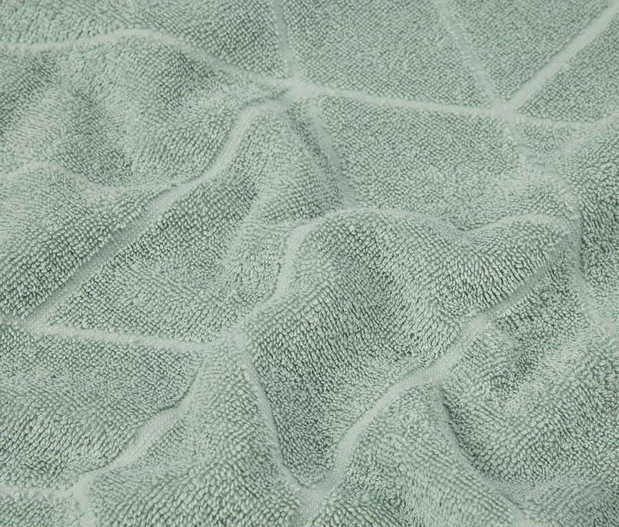 Gros plan d'une serviette vert menthe avec un motif géométrique en relief.