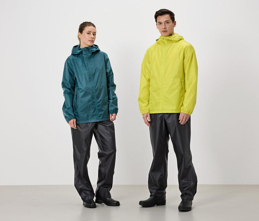 Une femme portant un imperméable turquoise et un homme portant un imperméable jaune se tiennent côte à côte sur un fond blanc. Ils portent tous deux des pantalons de pluie noirs.